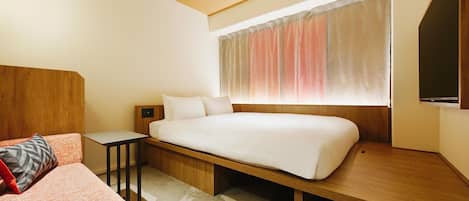 A modern hotel room with a bed, a bedside table, a nightstand, a sofa, and a large window with curtains.