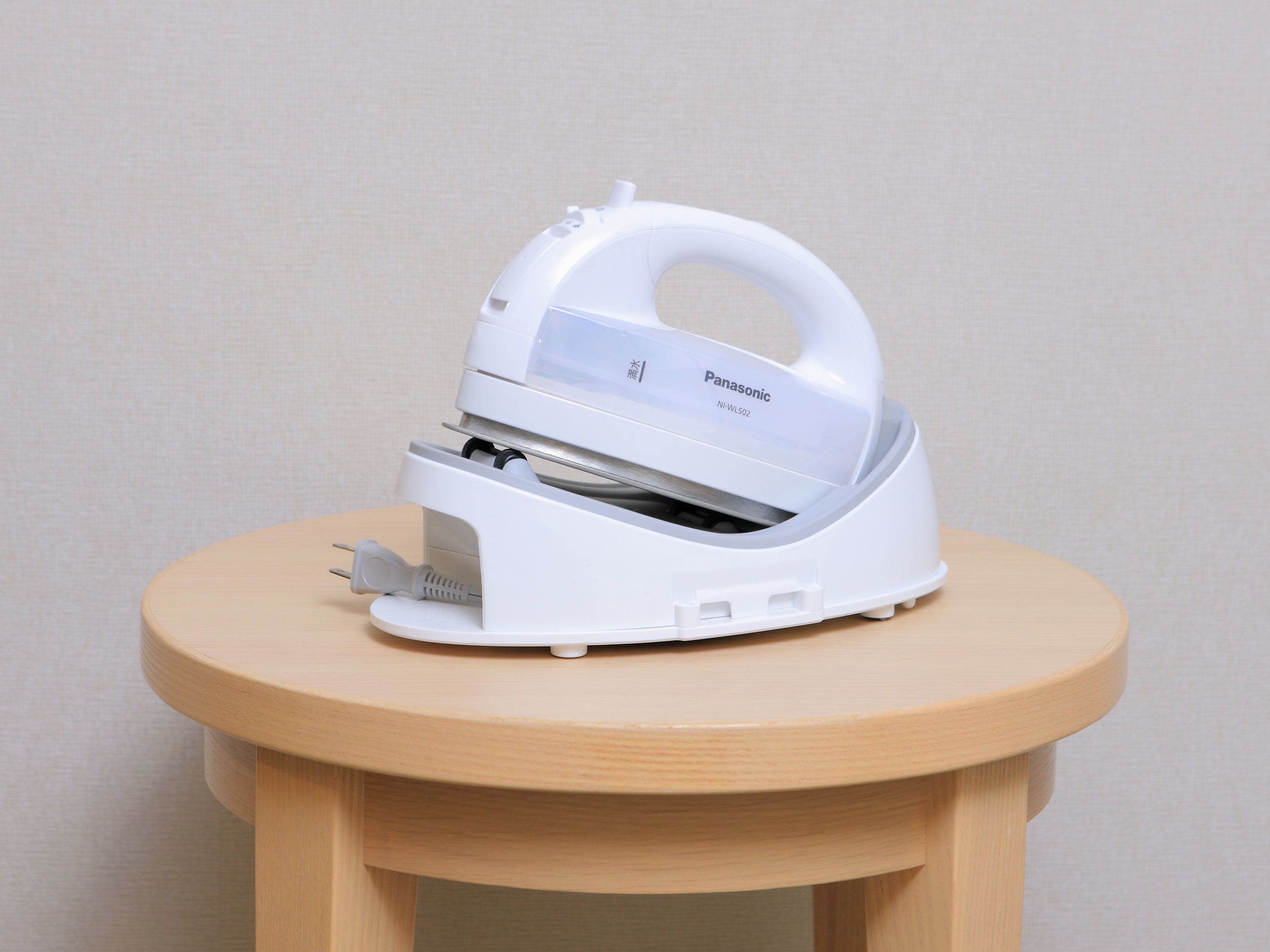 A white Panasonic iron on a small wooden table.