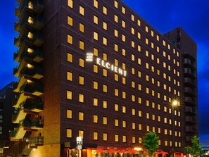 A multi-story hotel with a dark facade and illuminated windows.