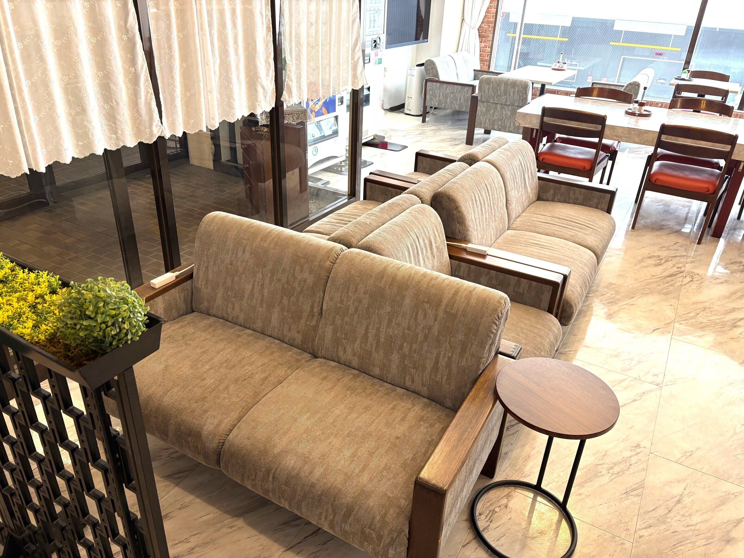 A seating area with sofas and a small table, a window with curtains, and a view of the street outside.