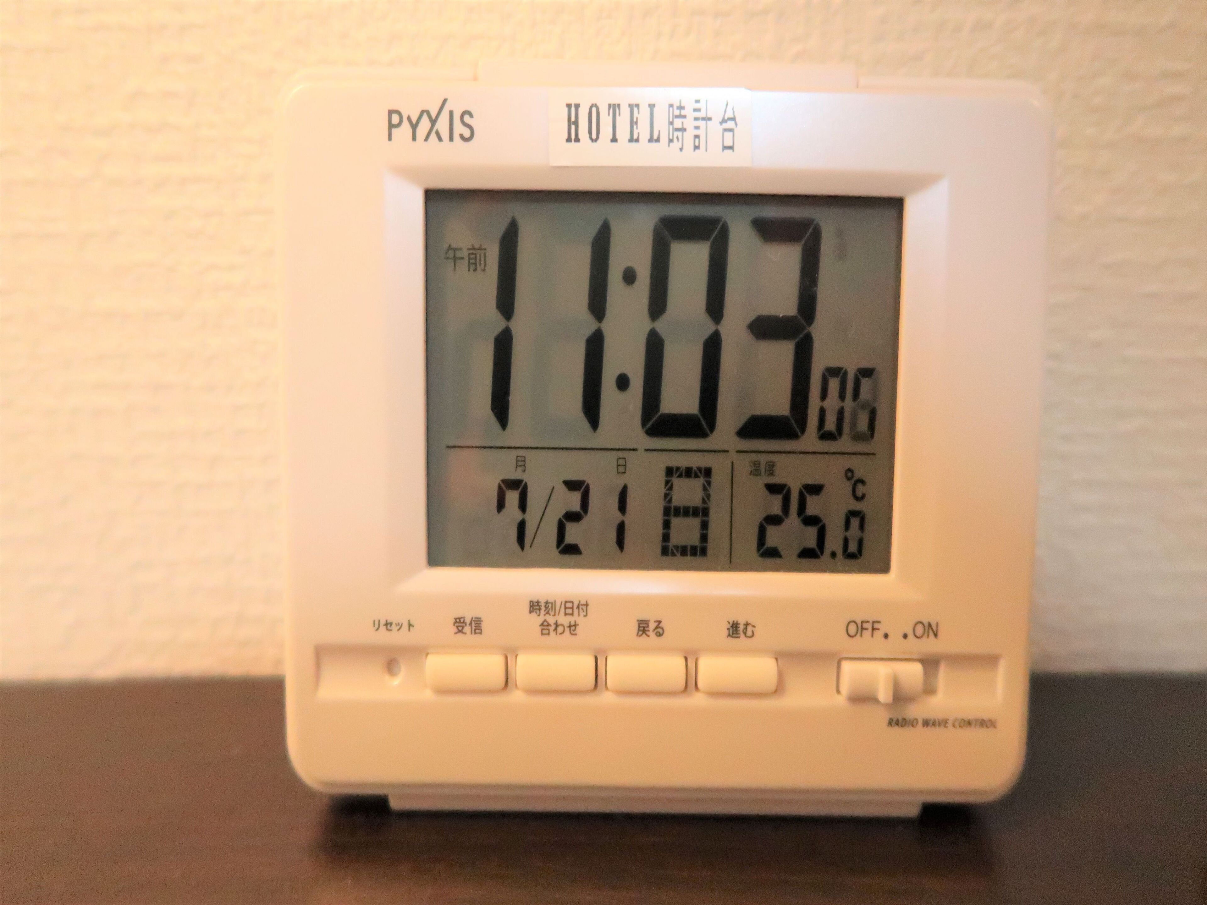 Een digitale hotelklok toont 11:03, de datum 21 juli, en een temperatuur van 25 graden Celsius.