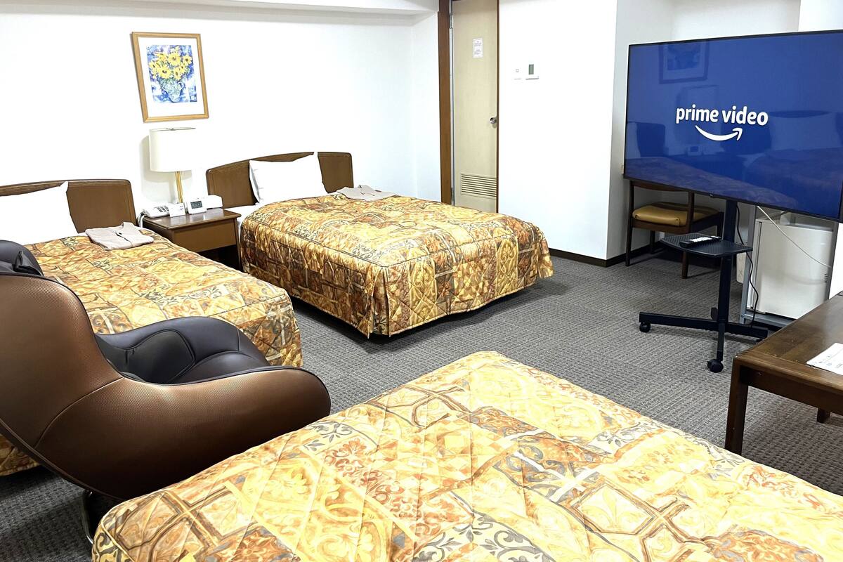 A hotel room with two beds, a TV, a desk, and a chair.