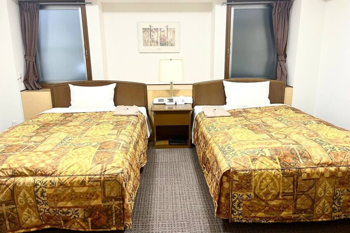 A hotel room with two beds, a desk, and a chair.