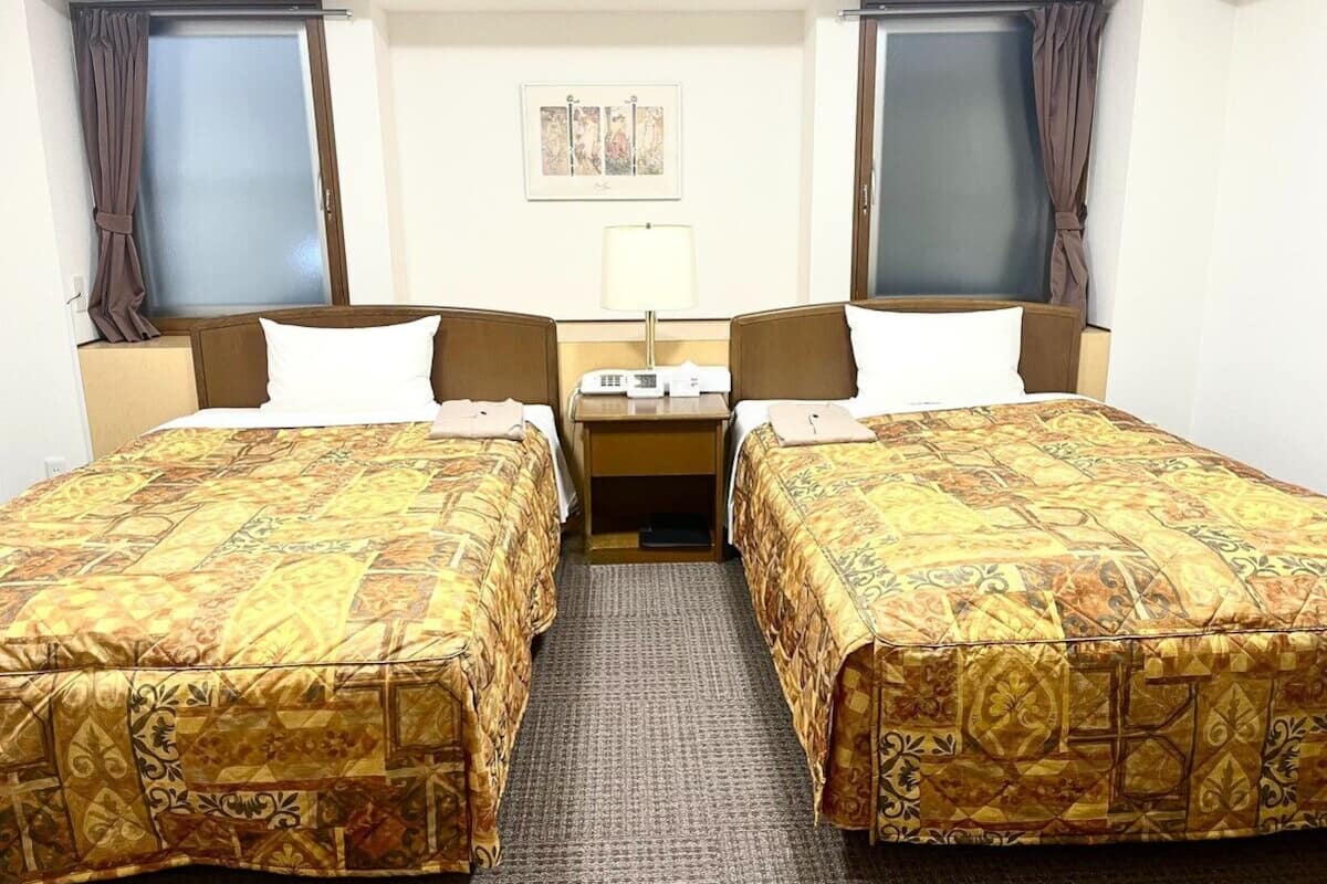 A hotel room with two beds, a desk, and a chair.
