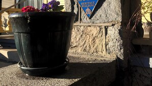 A stone pillar with a plaque reading "City of Vancouver Heritage Building" and a potted plant with flowers. - Windsor Guest House (Vancouver)