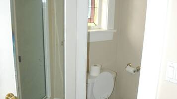 Ein Badezimmer mit Toilette, Duschkabine aus Glas und kleinem Fenster.