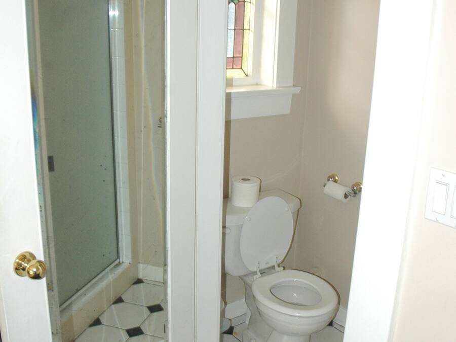 Ein Badezimmer mit Toilette, Duschkabine aus Glas und kleinem Fenster.