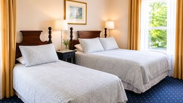 A hotel room with two beds, a nightstand, lamps, a framed picture on the wall, and a window with curtains.