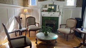 A traditional living room with a fireplace, patterned wallpaper, and wooden furniture. - Windsor Guest House (Vancouver)