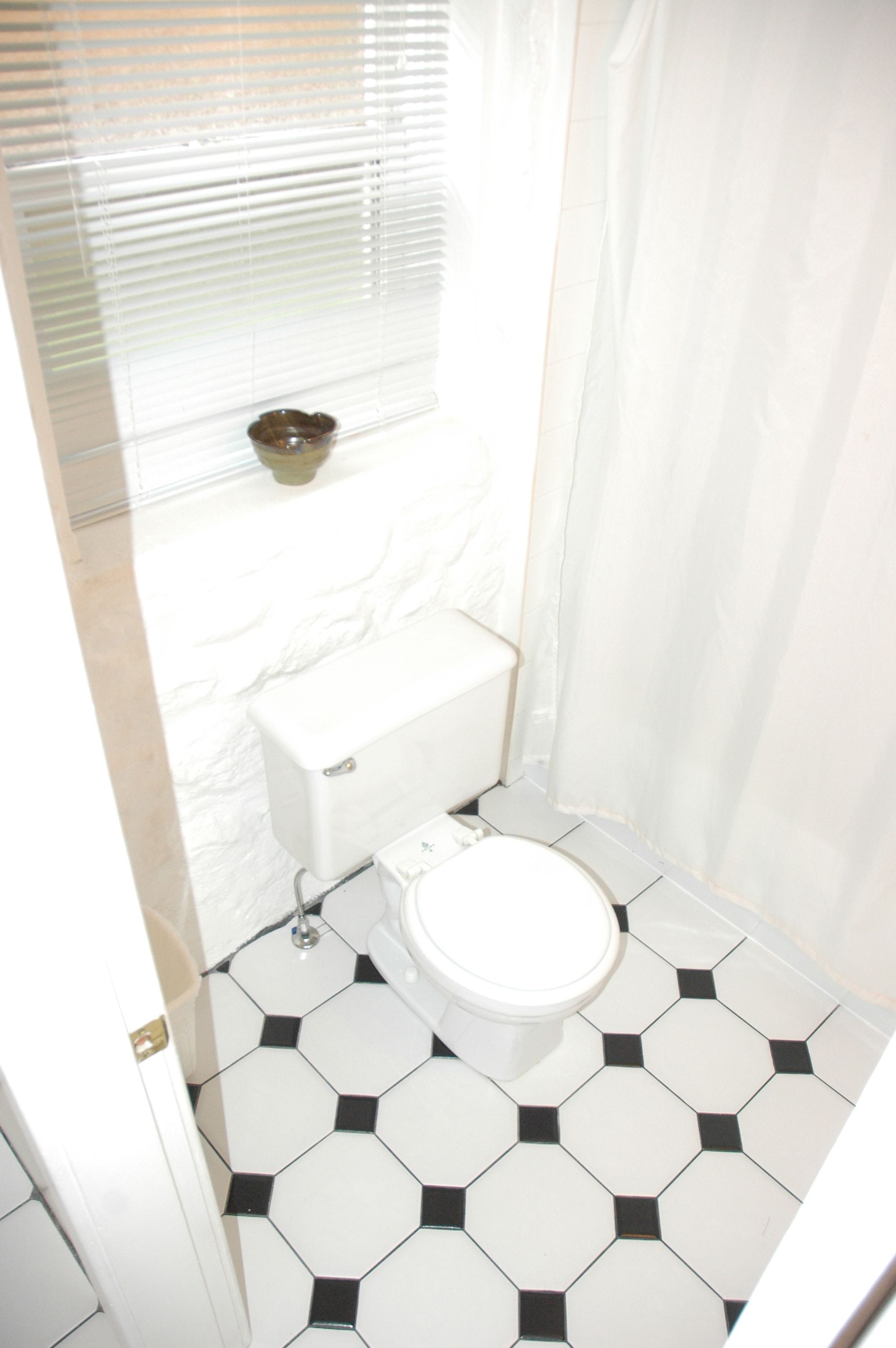 Een kleine badkamer met toilet, een witte wastafel en douchegordijn.