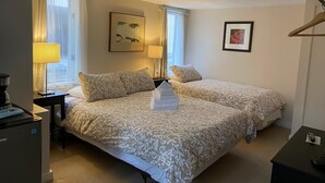 A hotel room with two beds, a desk, a coffee machine, and a heater. - Douglas Guest House (Vancouver)