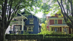 A two-story house with a balcony and a porch, surrounded by trees. - Douglas Guest House (Vancouver)