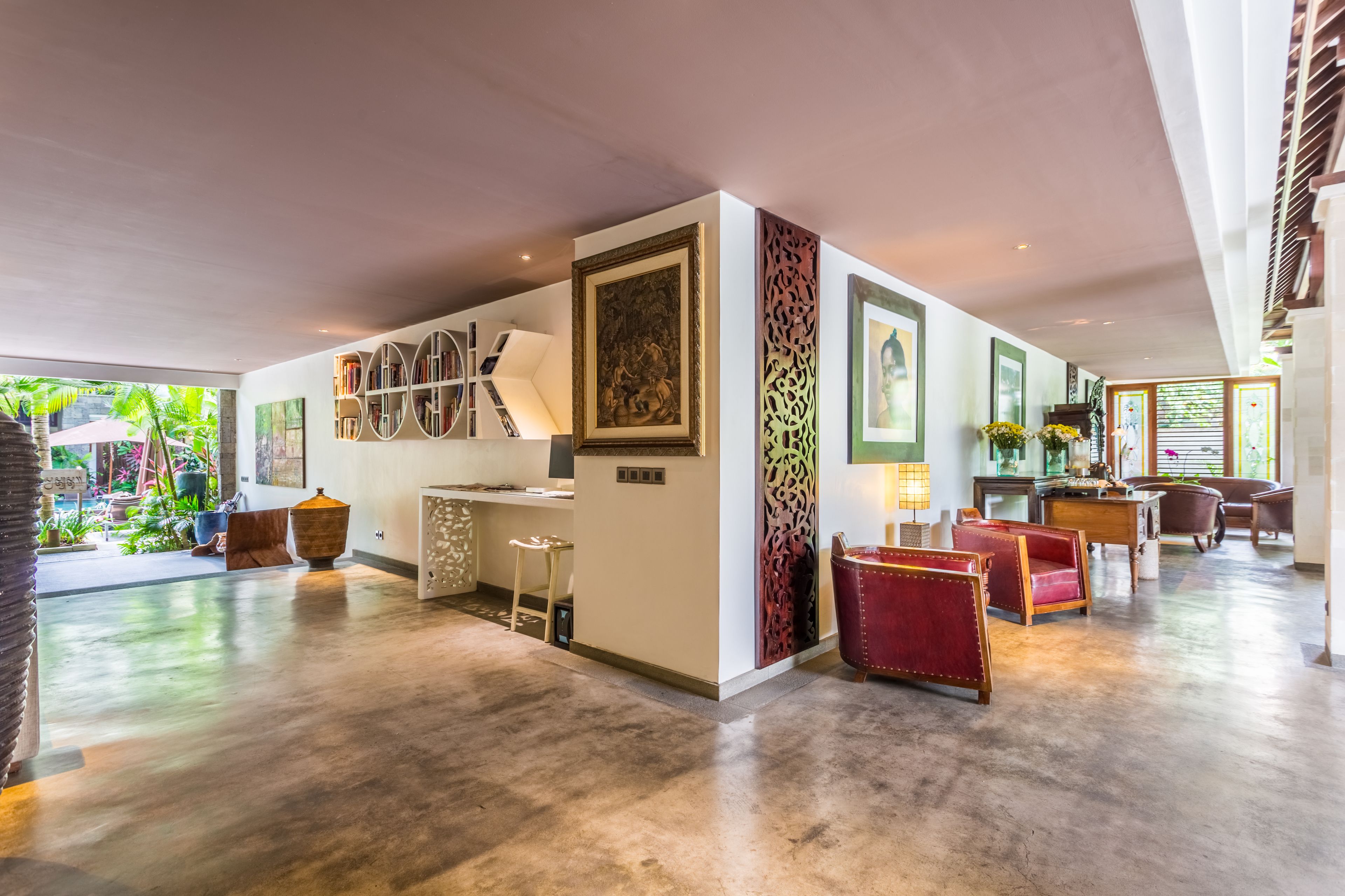 Amplia sala de estar con una gran estantería, comedor y una zona de estar con sillones tapizados en rojo.