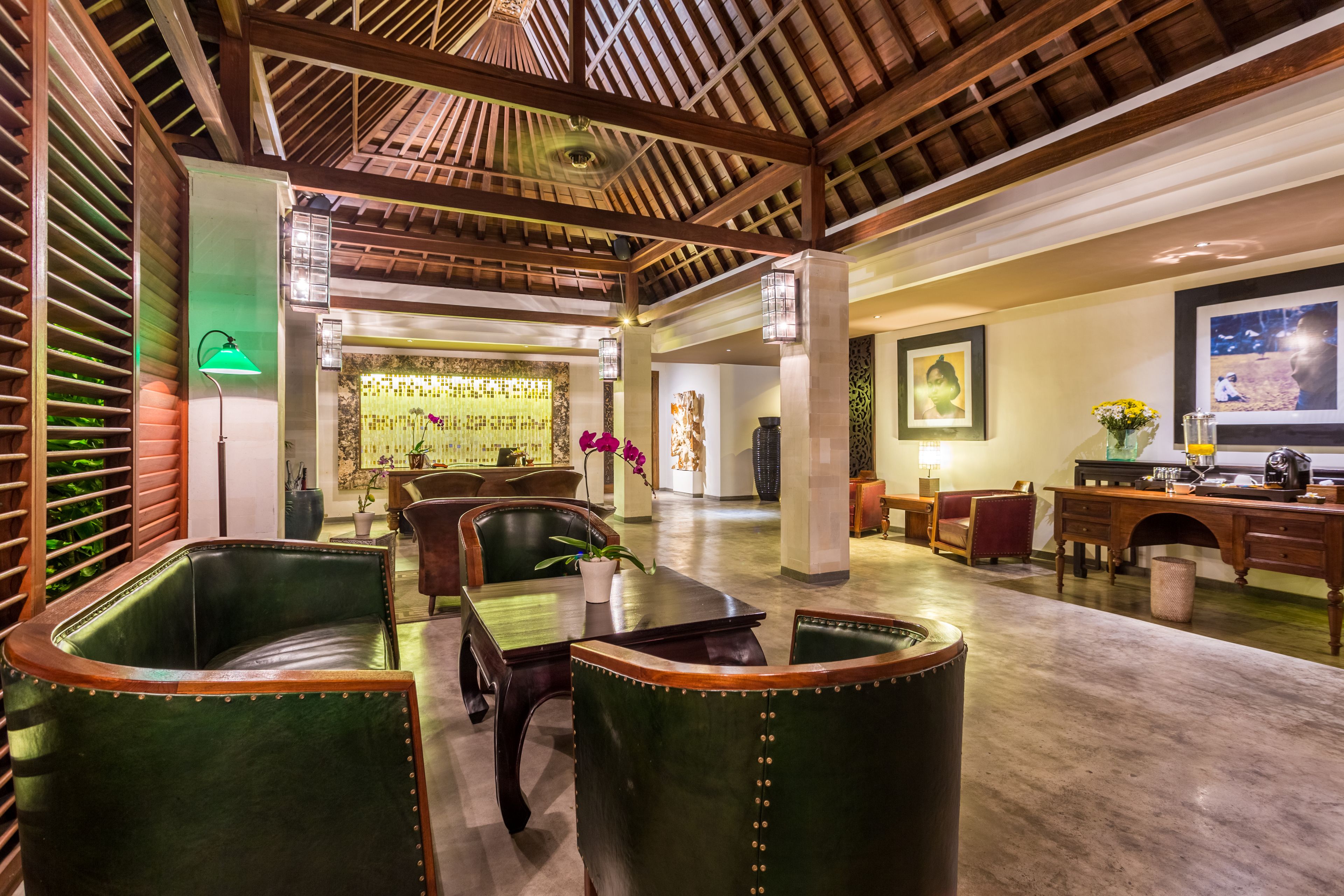 Un vestíbulo amplio con vigas de madera, sillones de cuero, un mostrador de recepción y una zona de comedor.