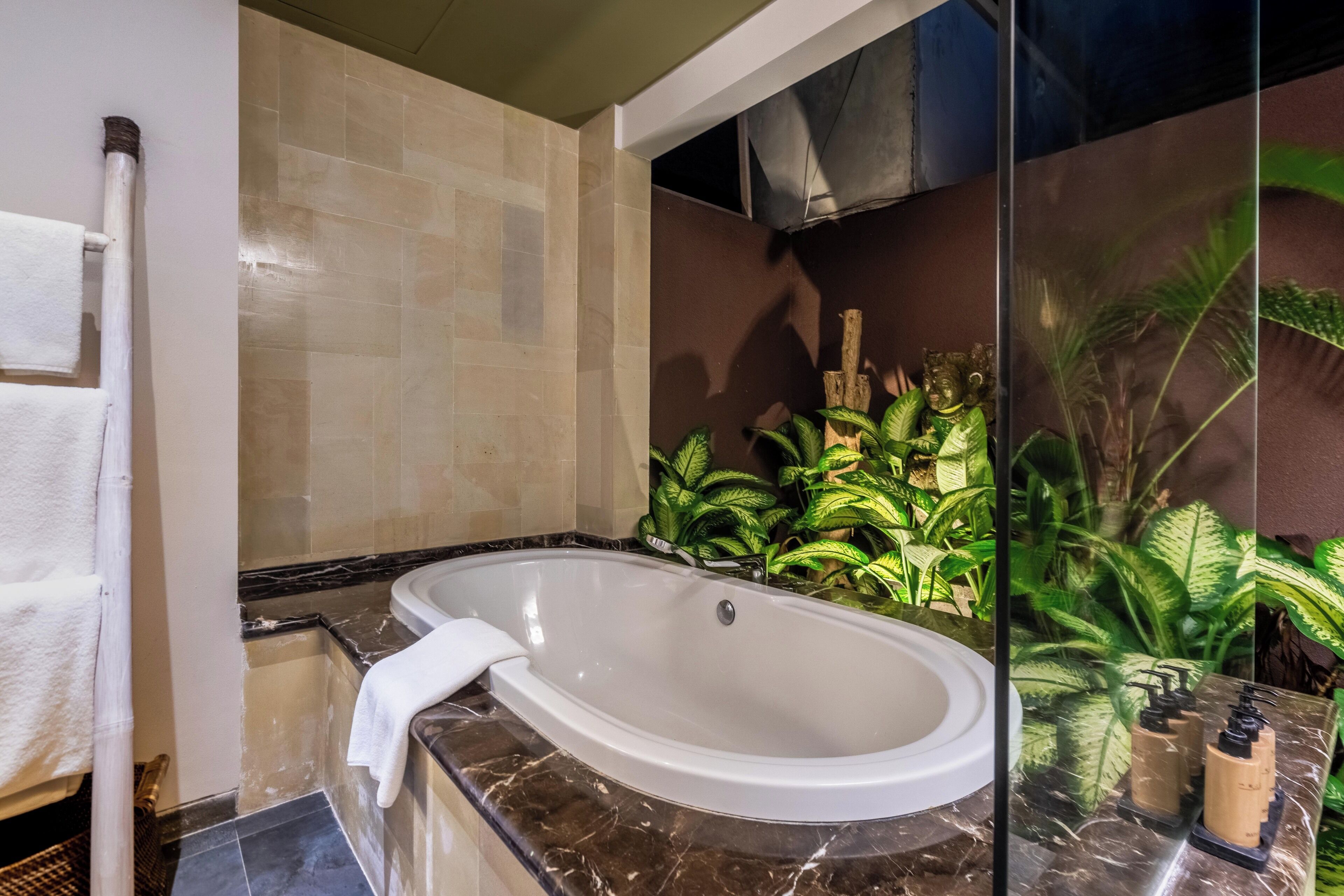 A modern bathroom with a large oval bathtub, a white towel, and a marble countertop.