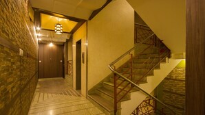 Un pasillo con una escalera, una puerta de madera y un suelo estampado.