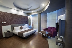 A modern hotel room with a large bed, a seating area, and a television. - Hotel Narula's Aurrum (Amritsar)