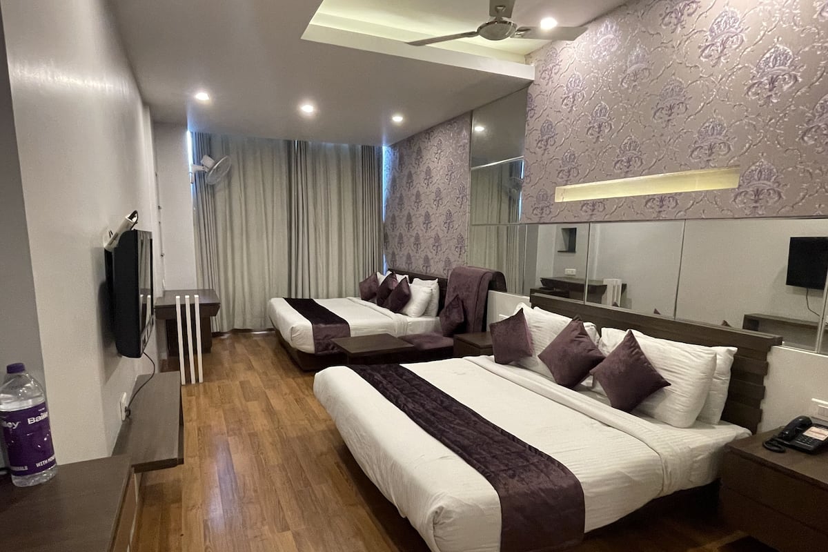 A hotel room with two beds, a mirror, a TV, and a water bottle.