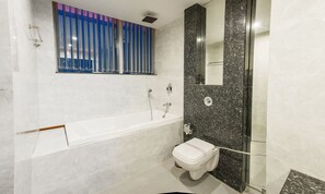 A modern bathroom with a bathtub, toilet, and shower area. - Hotel Narula's Aurrum (Amritsar)