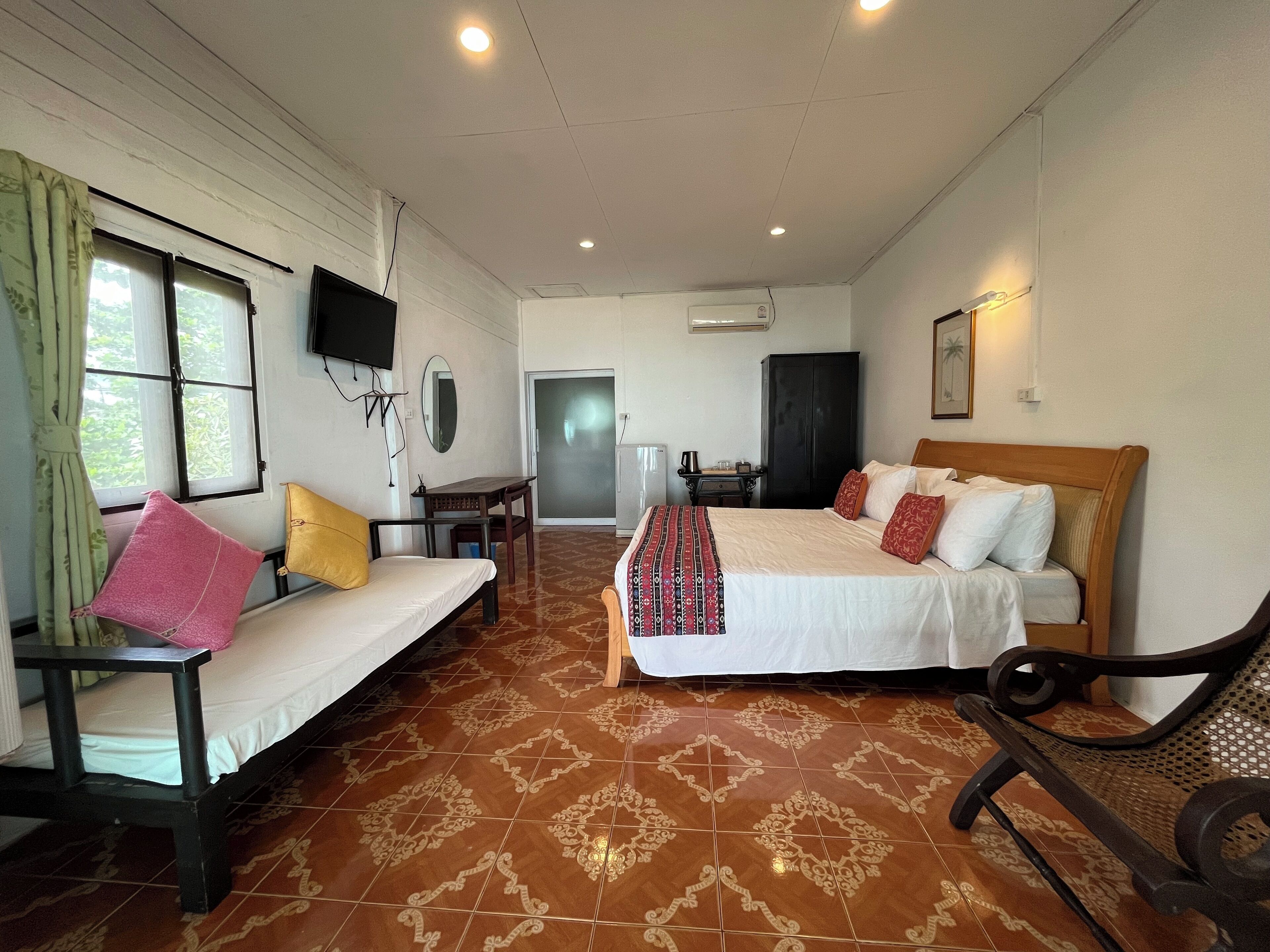 A hotel room with a bed, a sofa, a desk, and a TV.