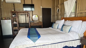 A neatly made bed with a blue and white bedspread, a wooden headboard, and a bedside table with a lamp. - Samui Harmony Resort (Koh Samui)