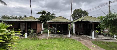 Una hilera de cabañas de madera con techos verdes, rodeadas de exuberante vegetación y palmeras.