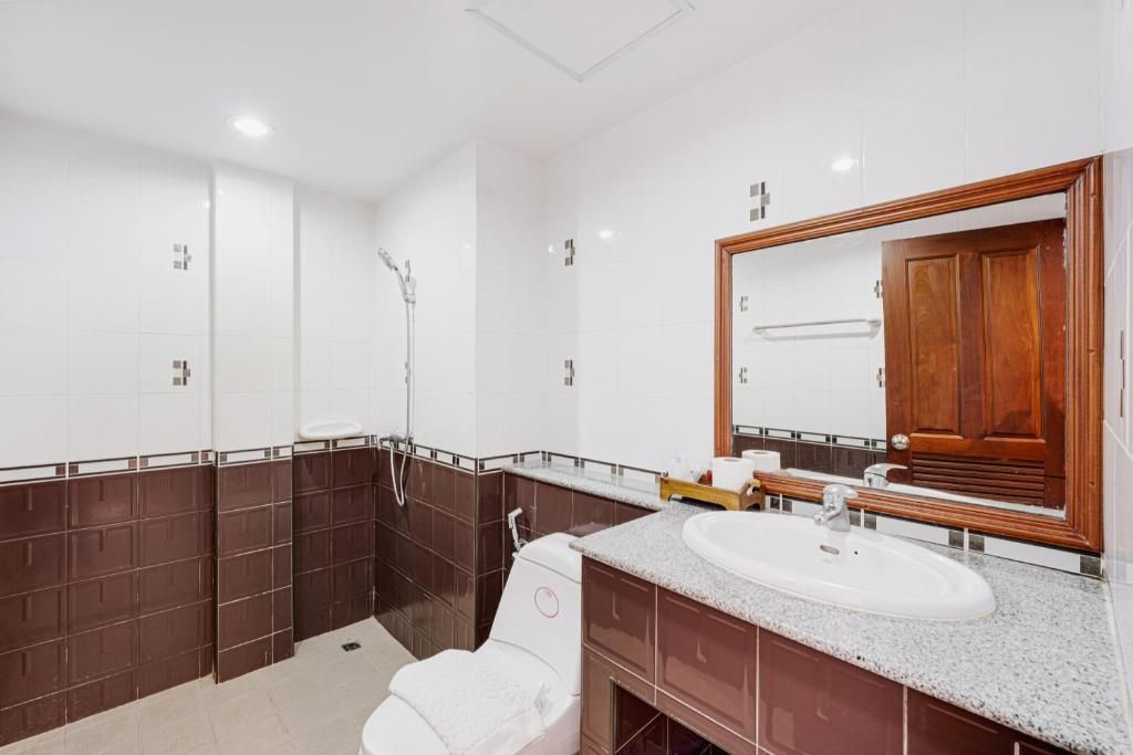 Une salle de bain moderne avec un lavabo blanc, un meuble-lavabo en bois et un grand miroir.