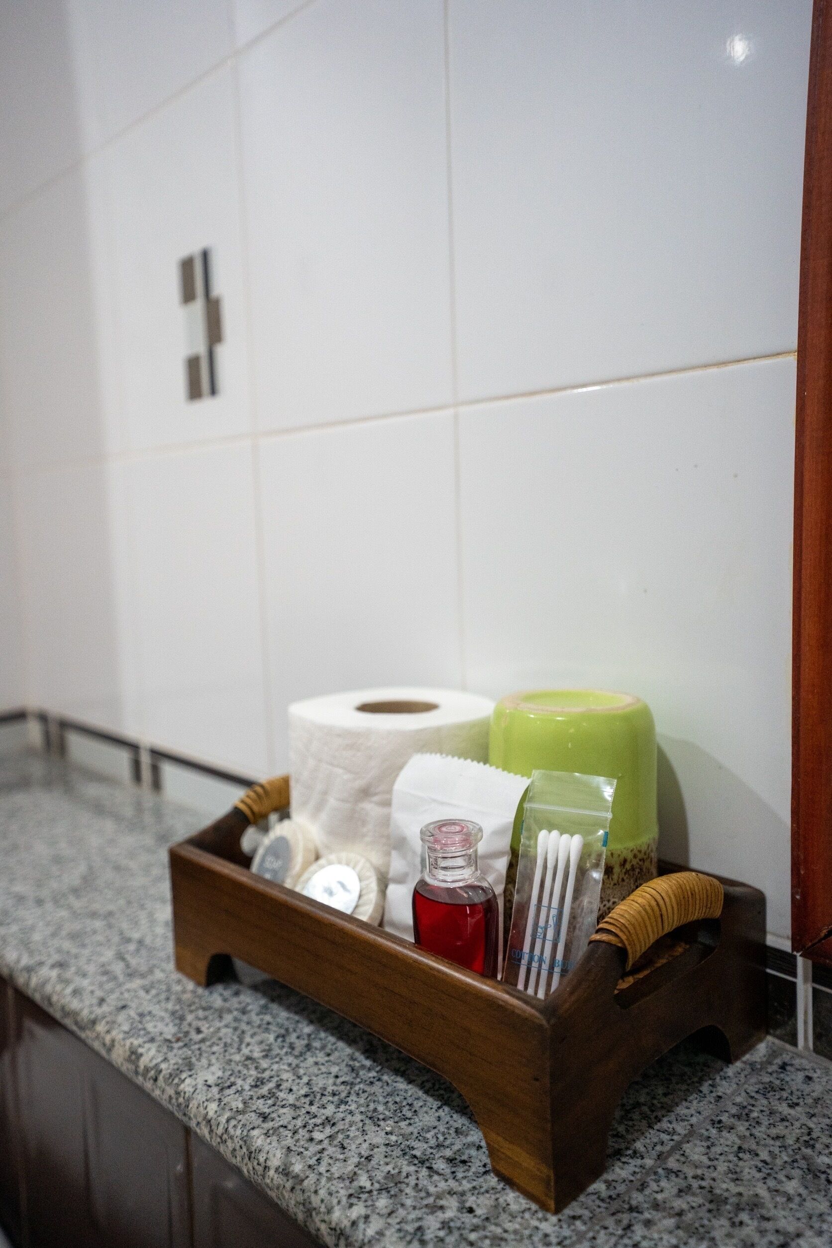 A wooden tray with toiletries on a granite countertop in a bathroom.