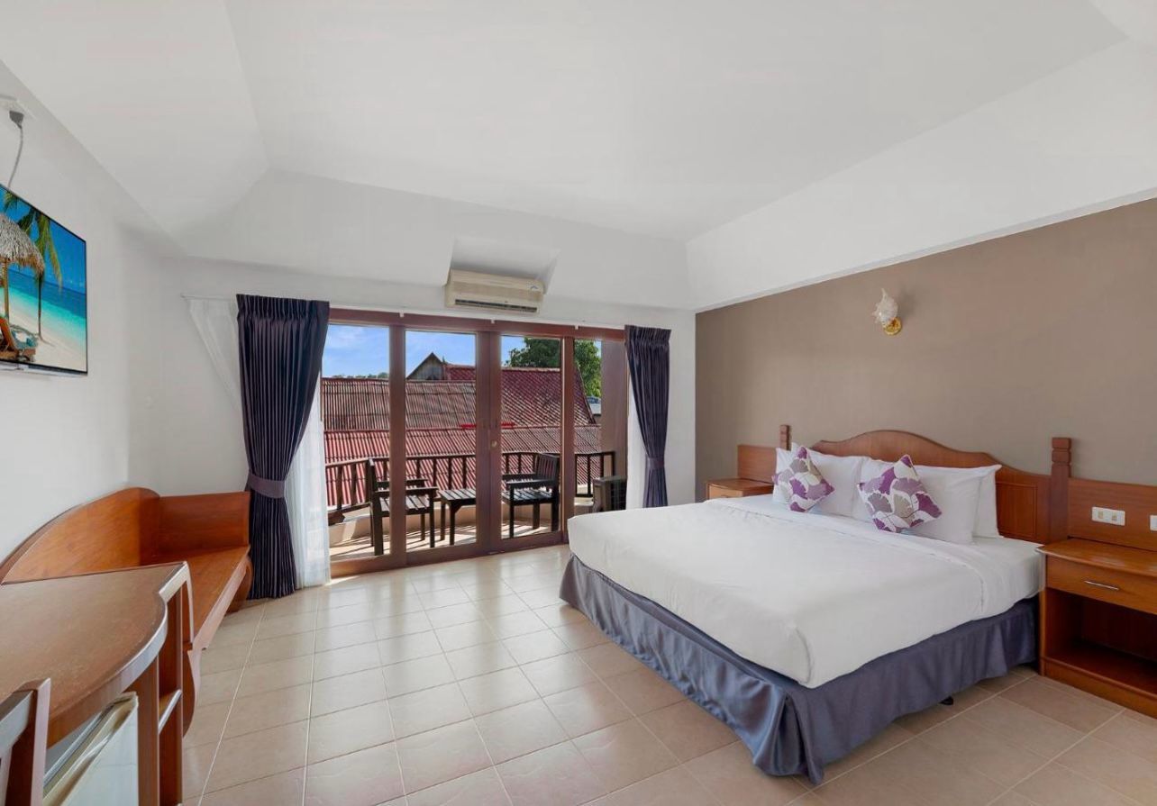 Habitación de hotel con cama, escritorio, silla y vistas al exterior.