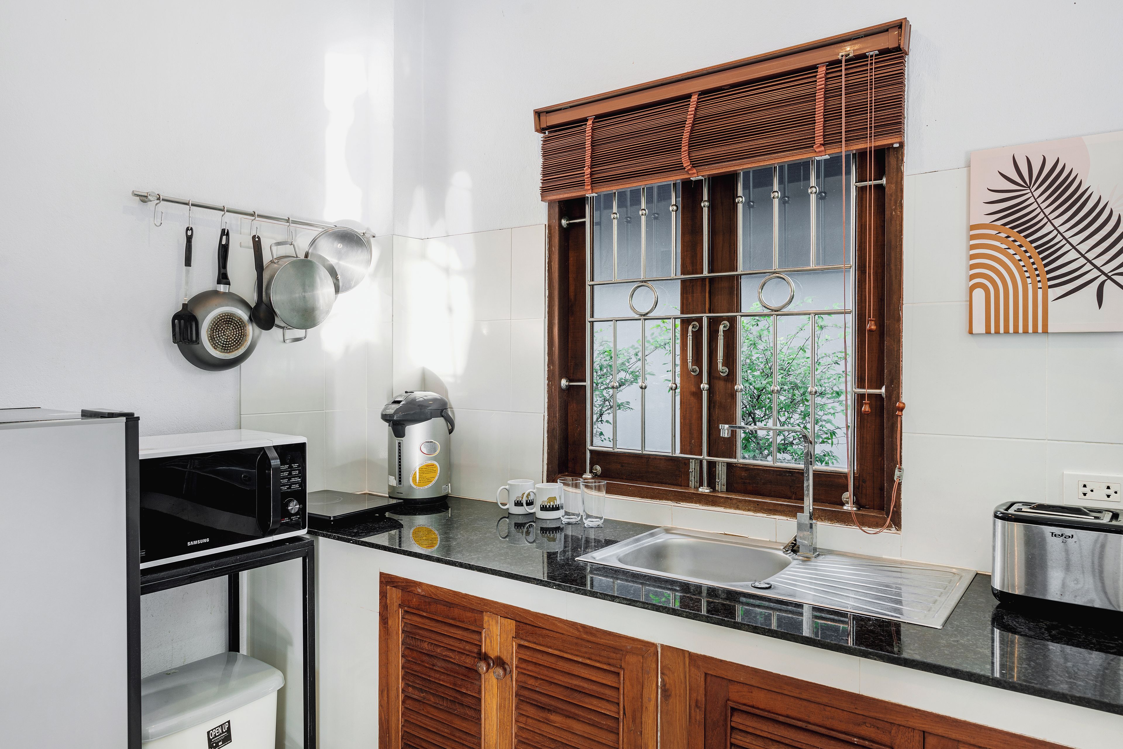 A kitchen with a microwave, coffee maker, and a window with a view of greenery.
