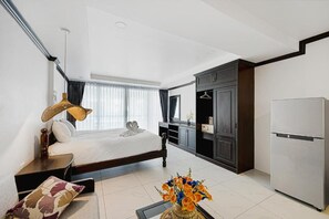 A modern hotel room with a bed, bedside table, lamp, and a decorative vase. - My Village Lamai (Koh Samui)