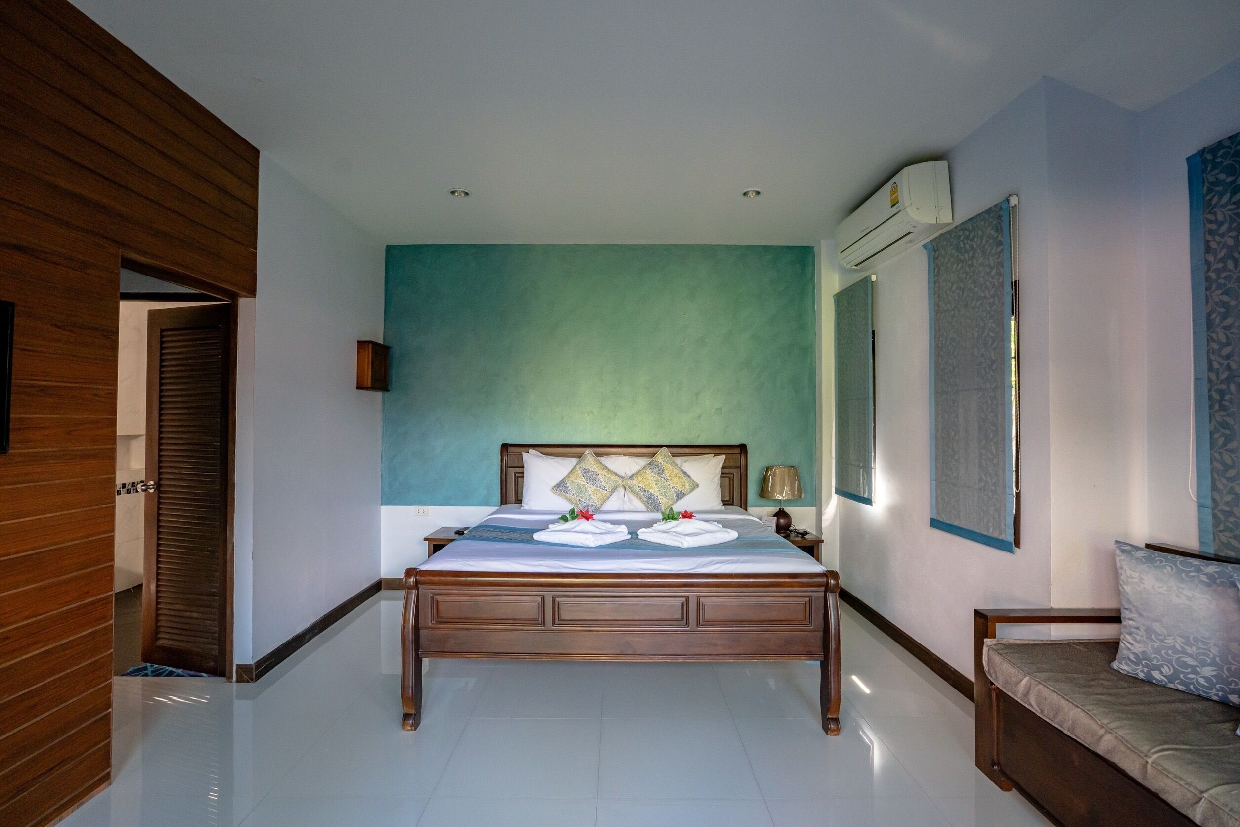 A hotel room with a wooden bed, a blue accent wall, and a large window.