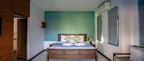 A hotel room with a wooden bed, a blue accent wall, and a large window.