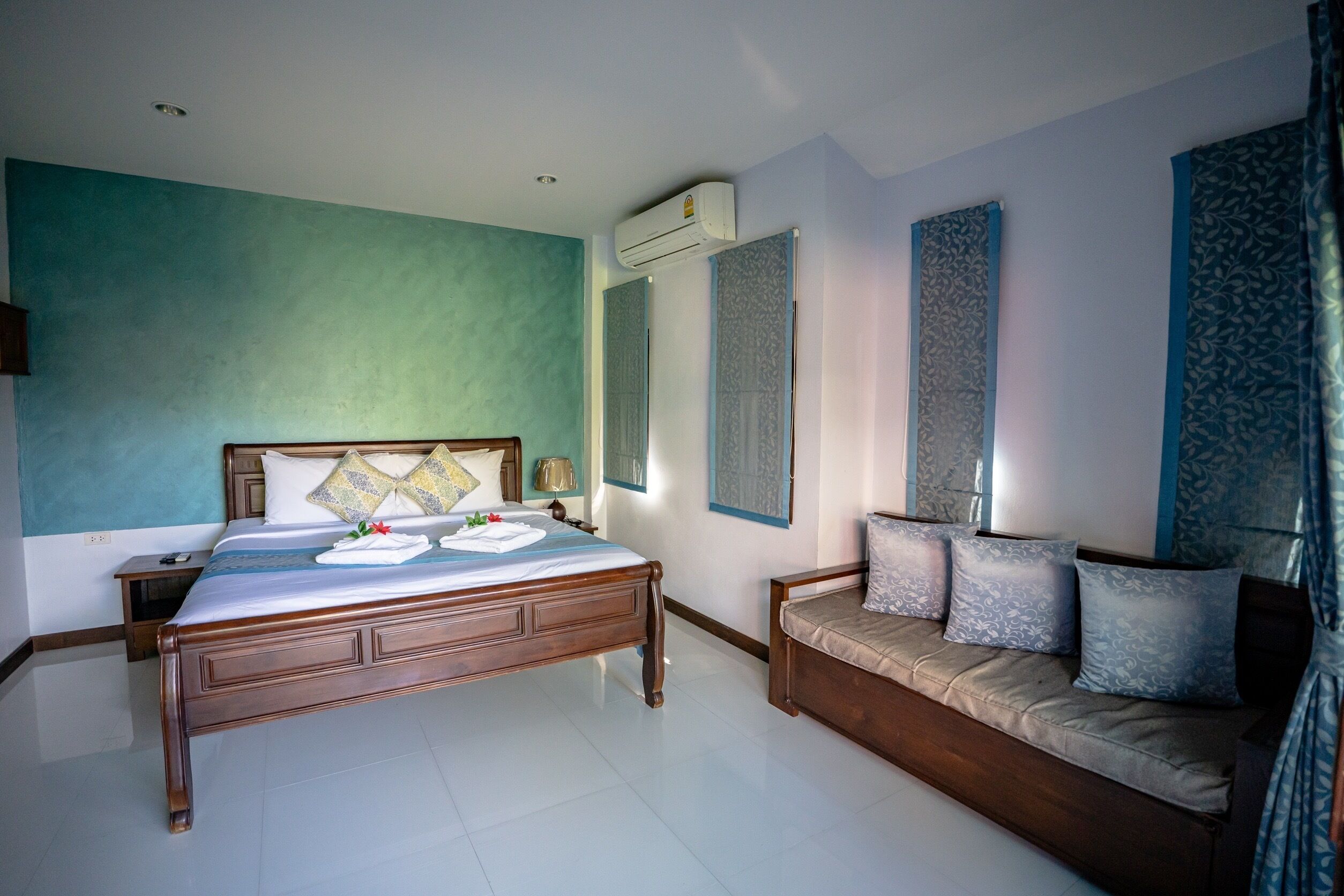 A bedroom with a wooden bed, a sofa, and a large mirror.
