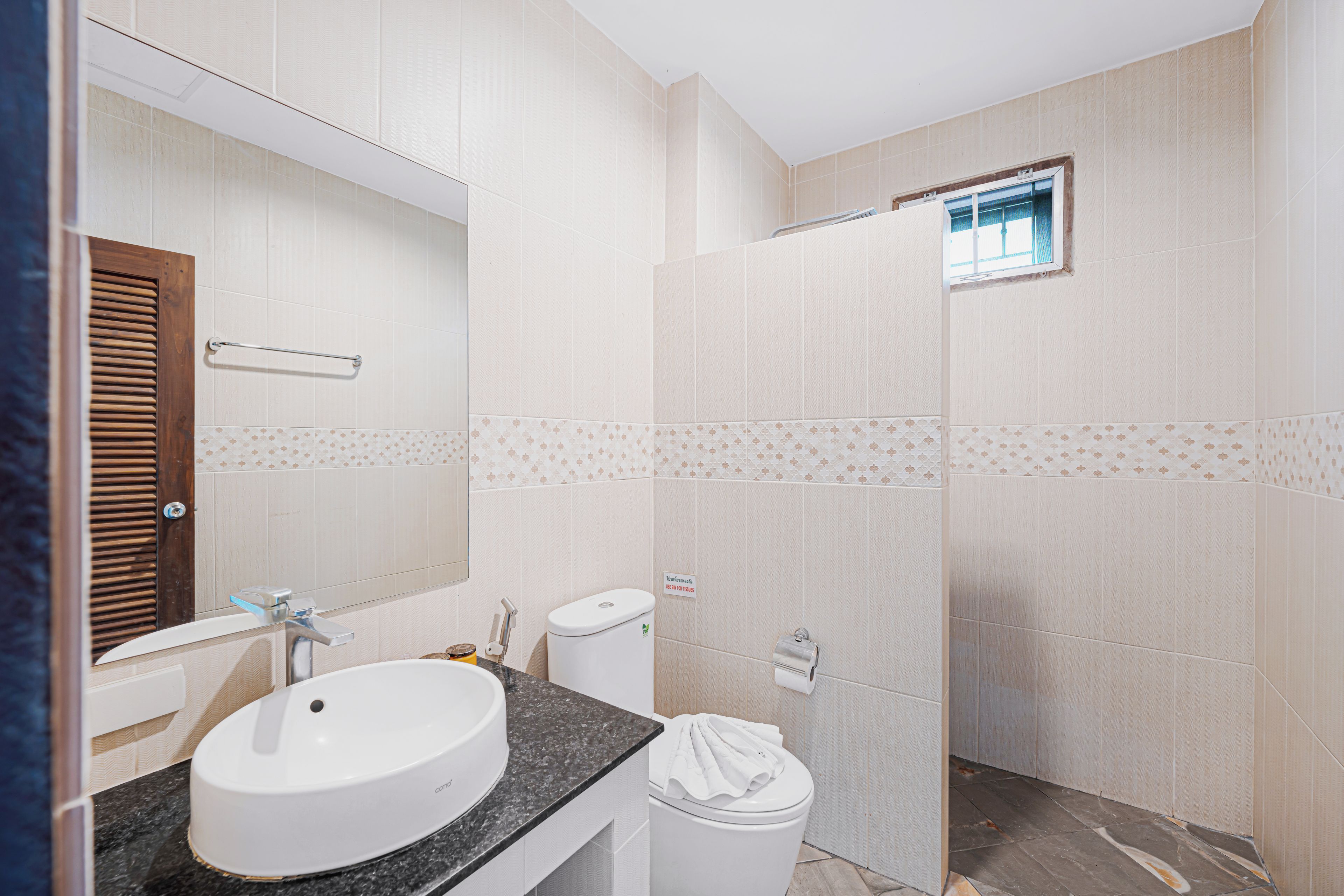 A bathroom with a sink, mirror, toilet, and shower area.