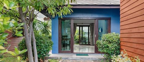 A modern house with a glass door entrance, a paved pathway, and a well-maintained garden.