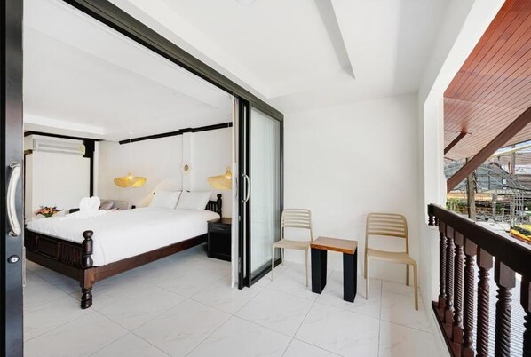 A bedroom with a bed, bedside tables, a chair, and a small table. - My Village Lamai (Koh Samui)