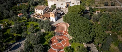 Vista aérea de un edificio histórico con un patio interior, rodeado de abundante vegetación.