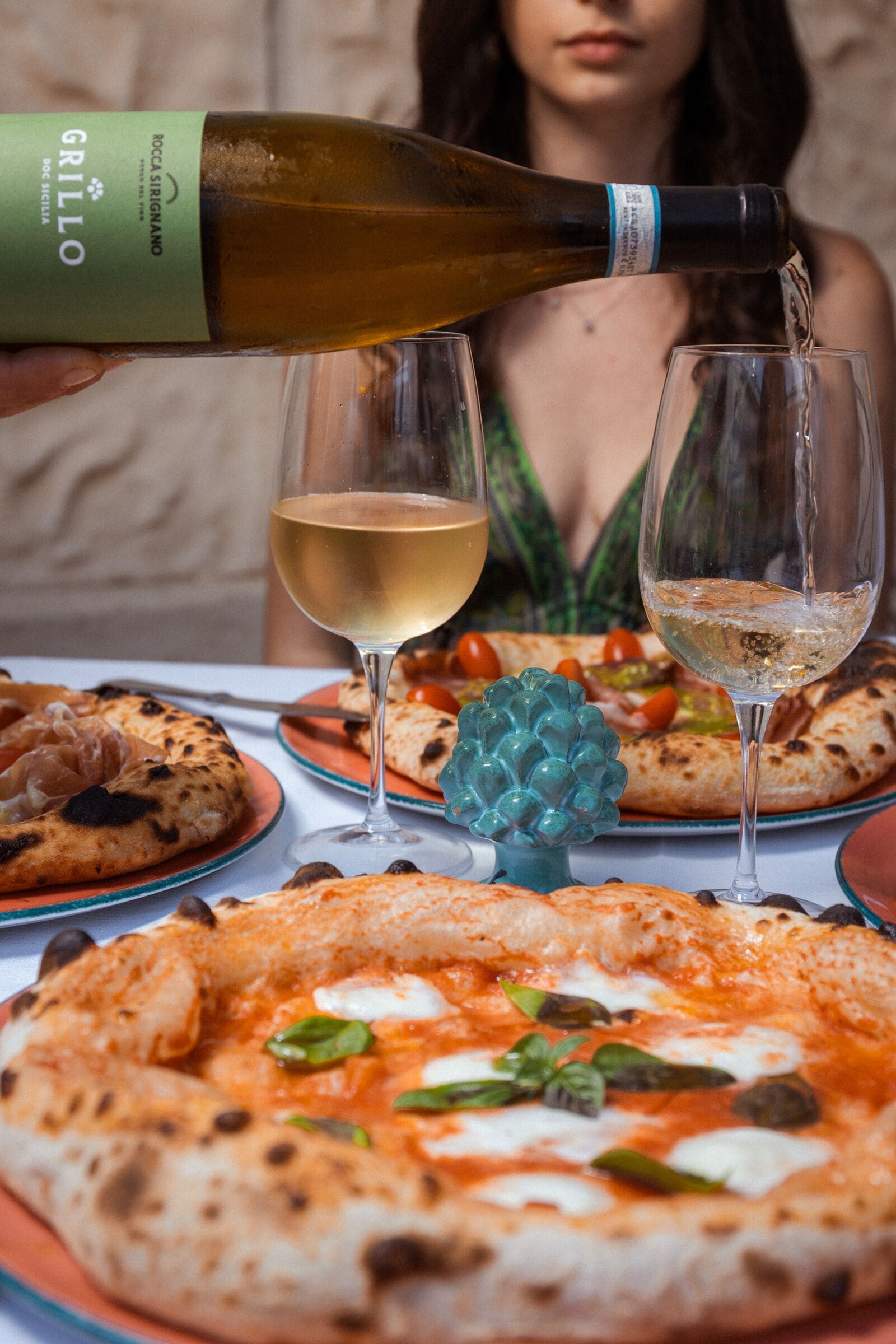 Ein Tisch mit einer Pizza, einer Weinflasche und zwei Gläsern.