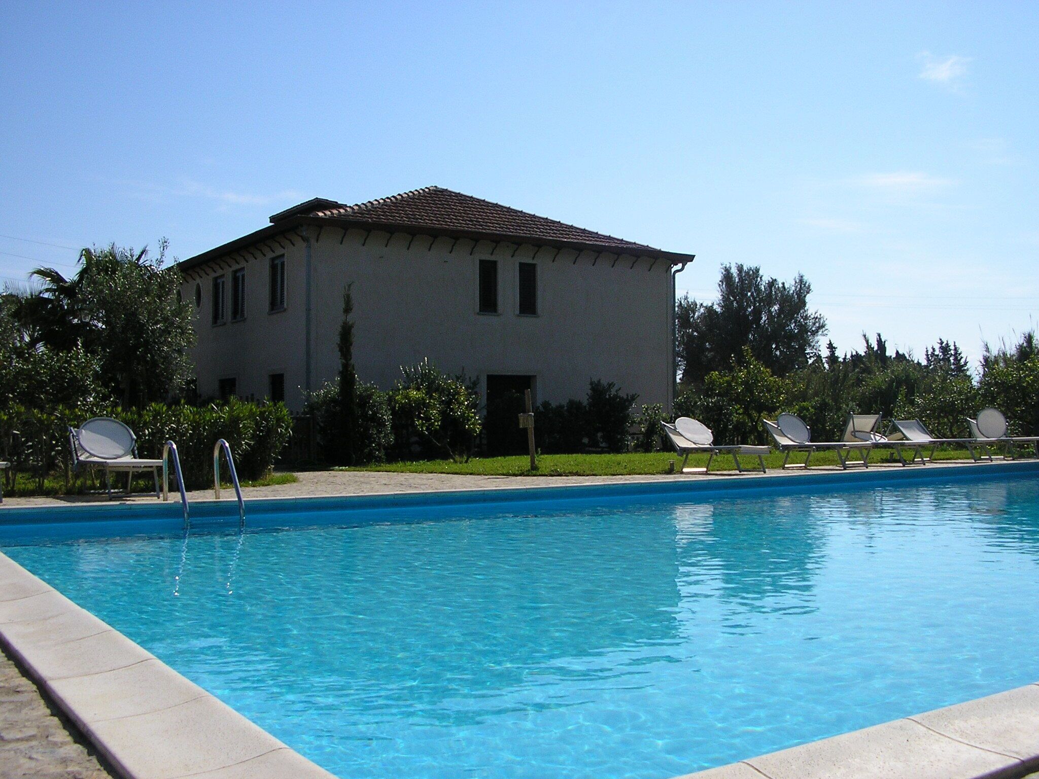 A swimming pool with lounge chairs and a building in the background.