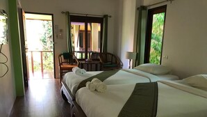 A hotel room with a large bed, a chair, a table, and a view of the outside. - Green Villa (Koh Samui)