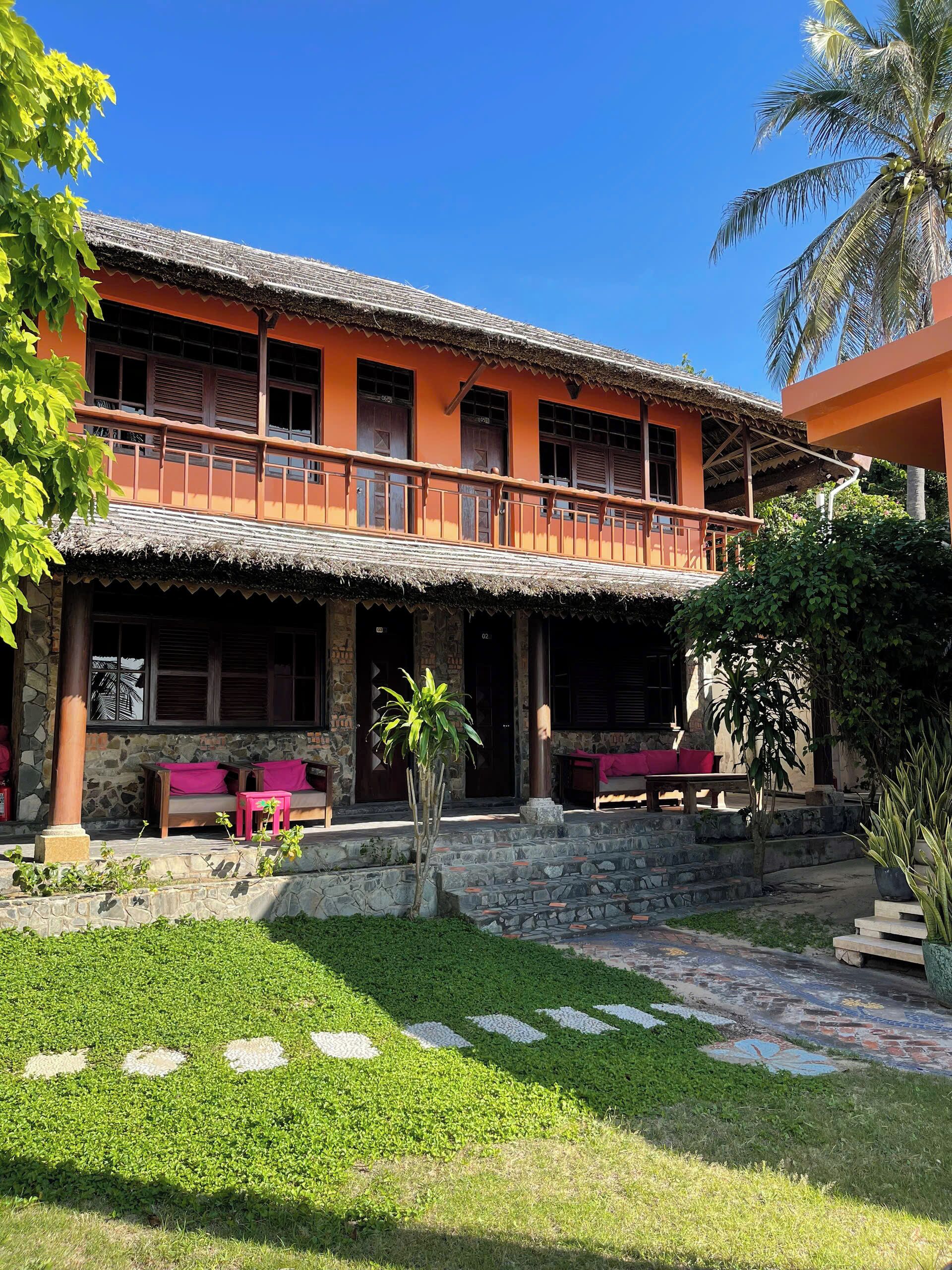 A two-story building with a balcony, stone steps, and outdoor seating.