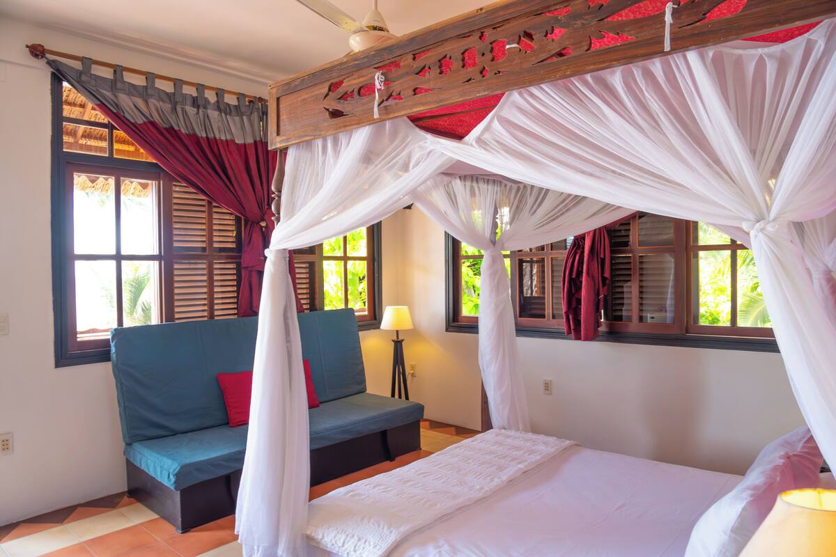 Un dormitorio con cama, sofá y ventana con cortinas.