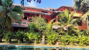 A pool area with a clear blue pool, surrounded by lush greenery and palm trees. - Full Moon Beach (Mui Ne)