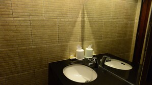 A bathroom with two sinks, a mirror, and a brick wall. - Vanda House Resort (Koh Samui)
