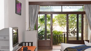 A hotel room with a bed, a TV, a desk, and a view of the outdoors. - Vanda House Resort (Koh Samui)