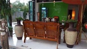 A wooden bench with a table and chairs, a small water feature, and a statue. - Vanda House Resort (Koh Samui)