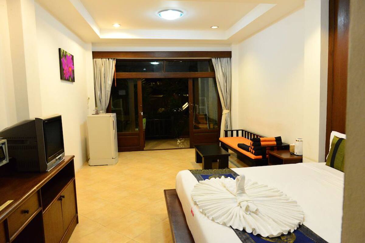 A hotel room with a bed, a television, a desk, and a view of the outside.