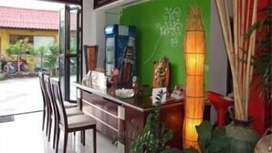 A reception area with a green wall, a reception desk, chairs, and a decorative lamp. - Vanda House Resort (Koh Samui)