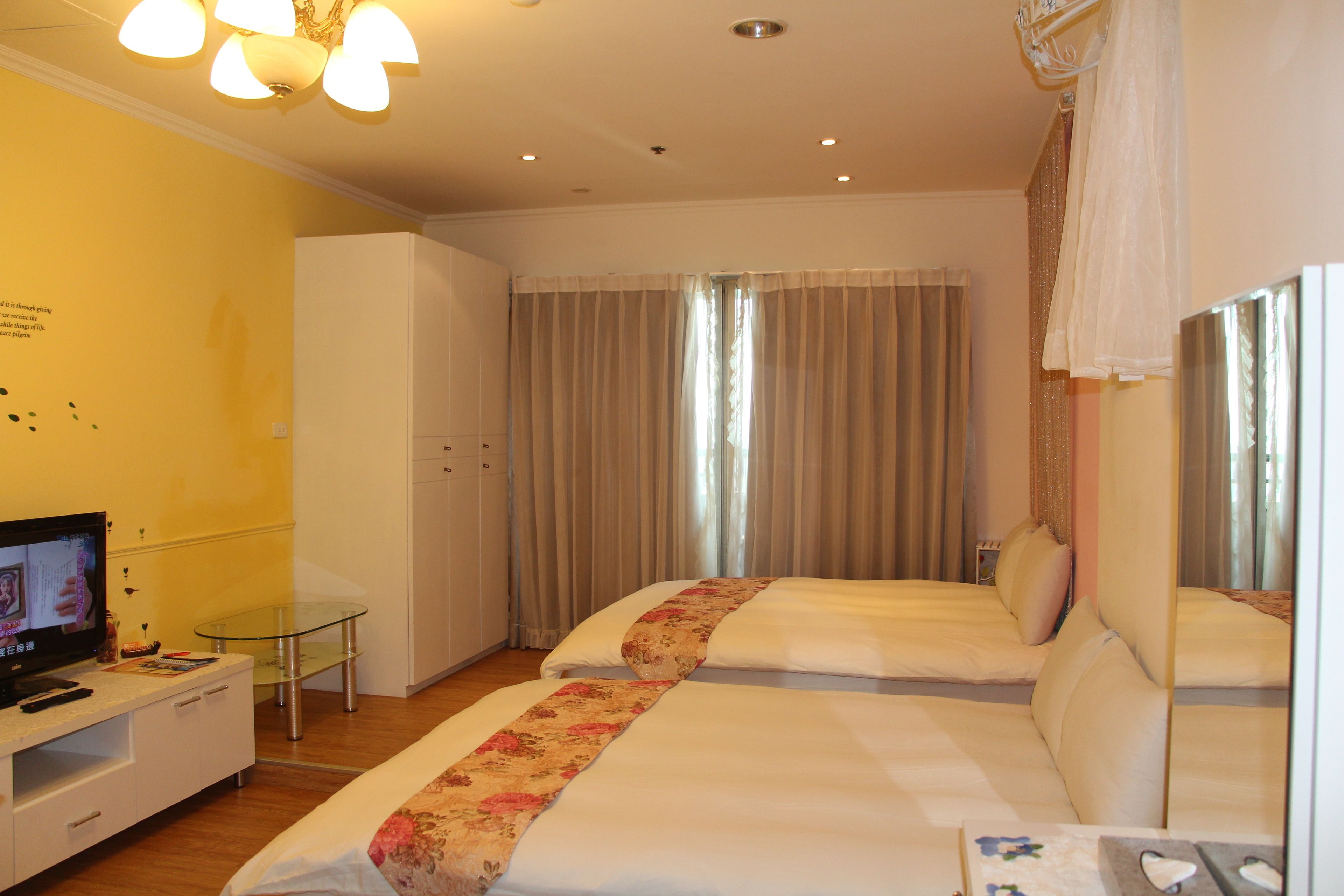 Habitación de hotel con dos camas, televisión, una mesita de vidrio y cortinas.